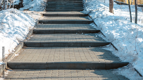 Obraz na płótnie Concrete block paved path bordered by a metal fence and snow going slightly uphi