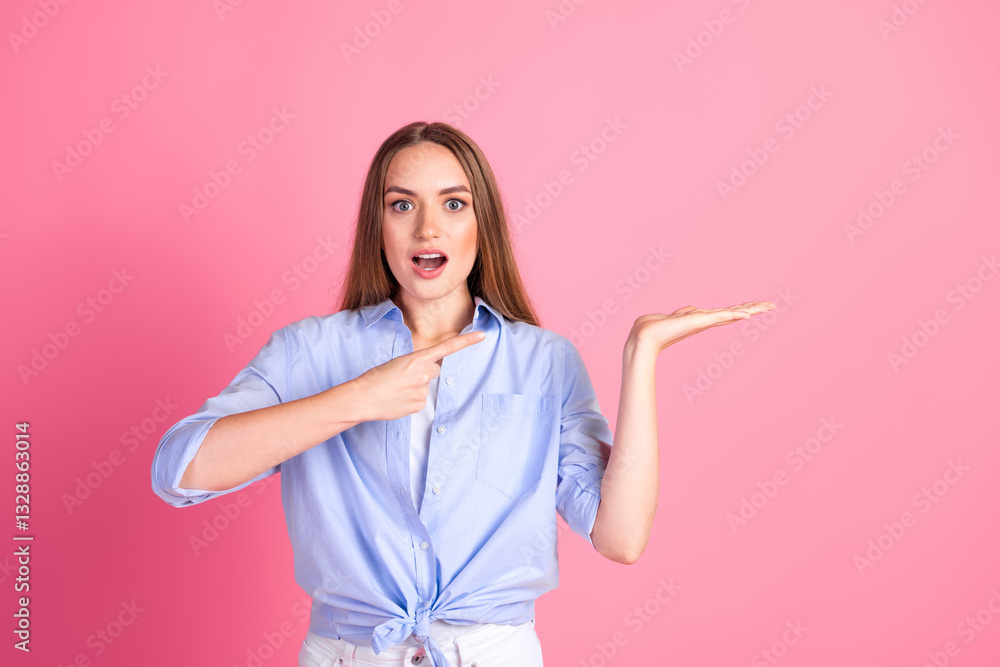 Young woman gesturing with hands, expressing surprise and curiosity while showcasing an empty space on a pink background Young woman gesturing with hands, expressing surprise and curiosity while showcasing an empty space on a pink background