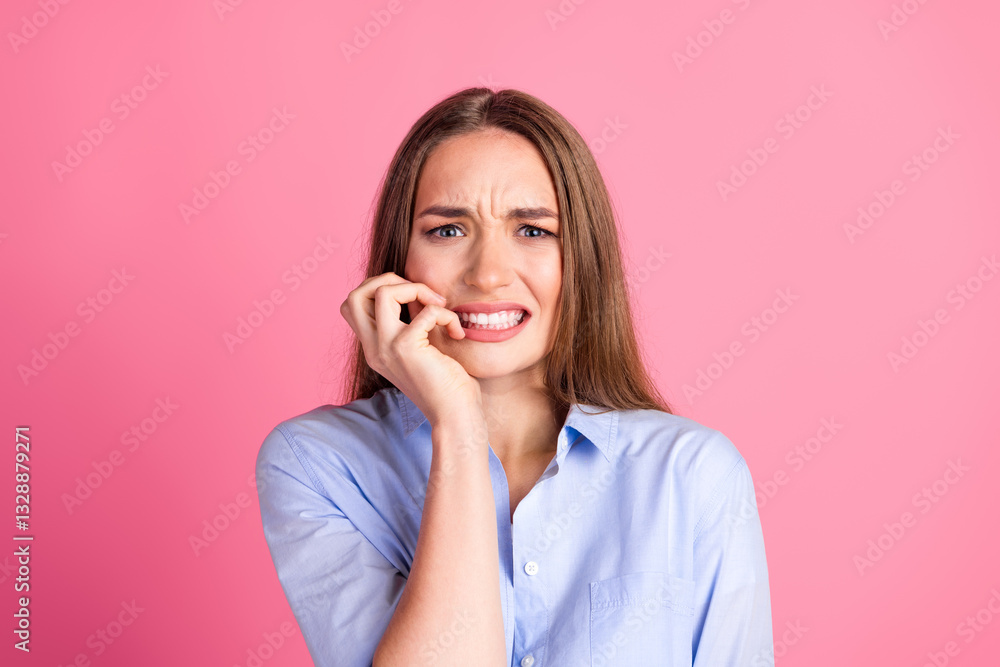 Fototapeta premium Young woman with long brown hair wearing a casual blue shirt showing a worried expression against a pink background