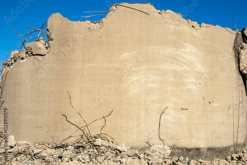Part of concrete wall with reinforcing bars at demolition site.