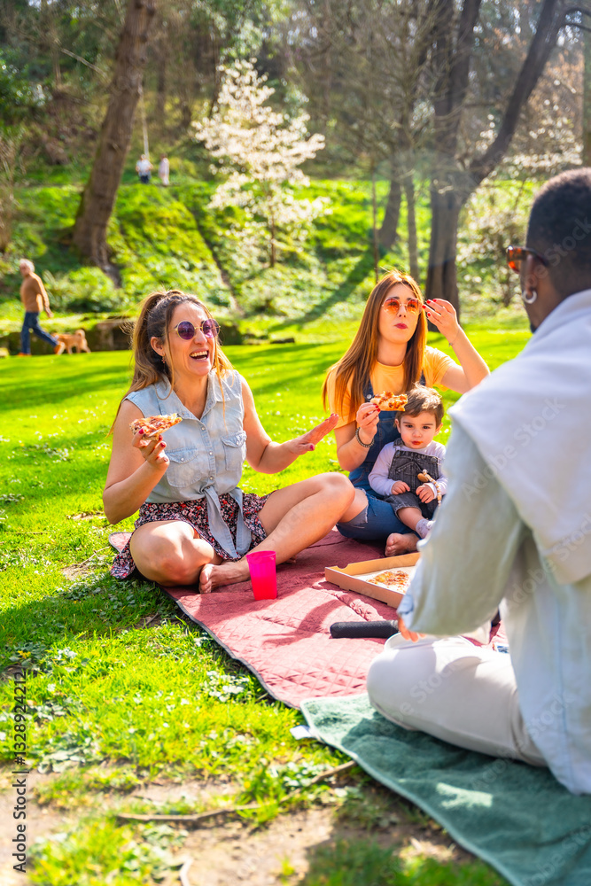 Fototapeta premium Happy family enjoying pizza at sunny park picnic