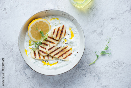 Foto Bowl with greek tzatziki sauce and grilled halloumi, horizontal shot on a white