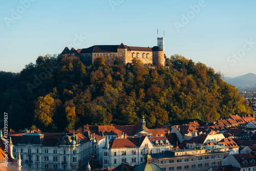 View of ljubljana castle on a hillside surrounded by vibrant autumn trees and picturesque rooftops, ljubljana, slovenia.