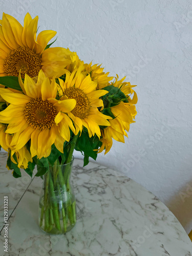 Obraz na płótnie A bouquet of sunflowers stands in a glass vase on a marble table in a white kitchen w salonie