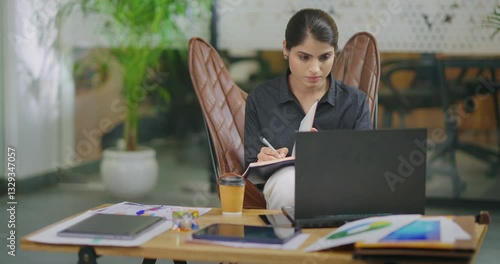 Indian gen z busy woman lady sitting chair use laptop on desk table look screen check email job office place young adult expert girl staff female do online work search day task data new idea planing