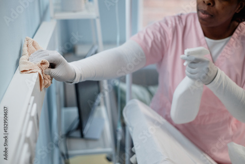 Fotografía Black person cleaning hospital room with disinfectant spray and cloth, ensuring