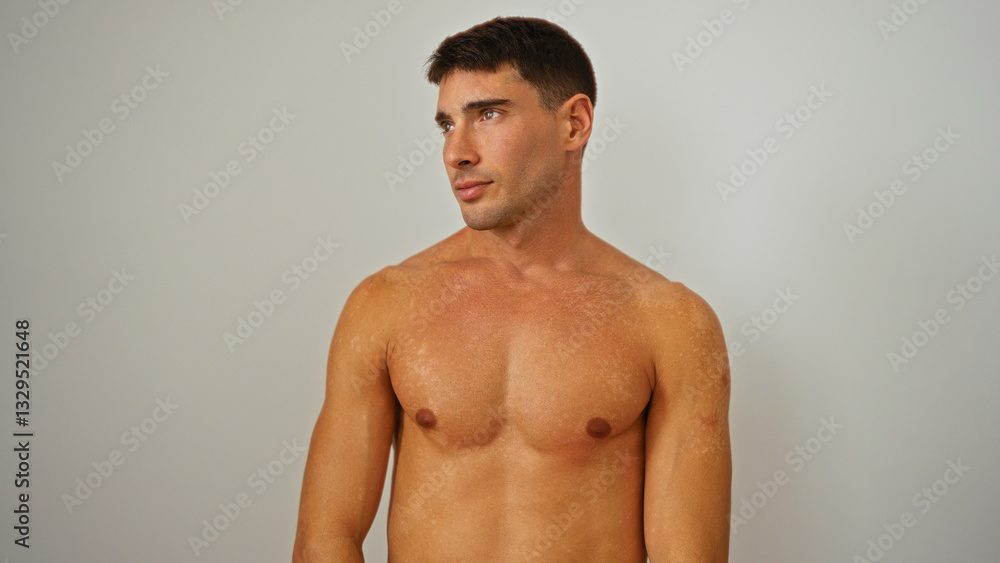 Fototapeta premium Young man posing shirtless against a white background showcasing confidence and attractiveness in a minimalistic portrait setting conveying simplicity and elegance.