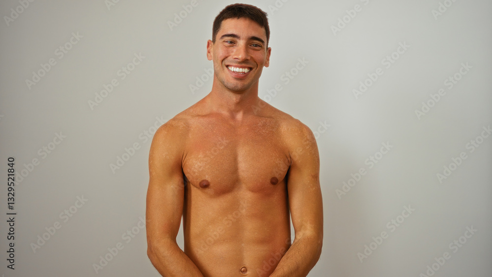 Fototapeta premium Young hispanic man smiling confidently over an isolated white wall background, showcasing a handsome and attractive adult male portrait with warmth and charisma.