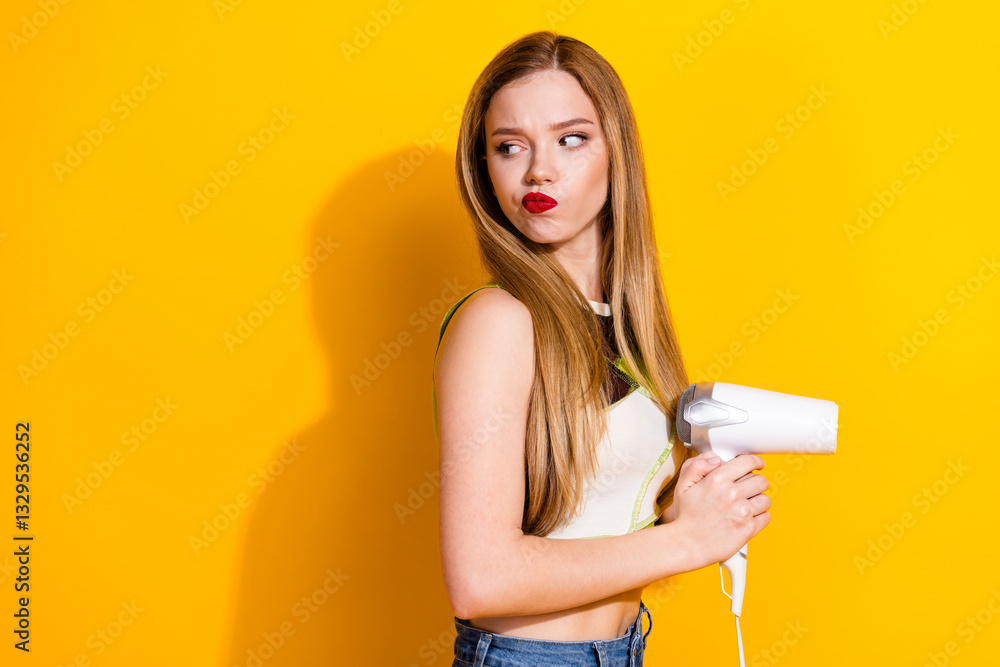 Young cheerful woman holding a hair dryer against a yellow background, expressing fun and confidence in a bright and casual outfit. Young cheerful woman holding a hair dryer against a yellow background, expressing fun and confidence in a bright and casual outfit.
