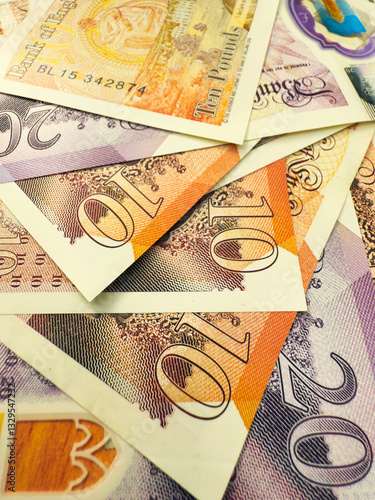 Macro closeup of British sterling paper bank notes currency – £10 and £20 – randomly spread out.