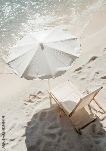 A high-angle shot of a white beach umbrella and chair on sandy shores, showcasing minimalist design with sunlight and shadows in neutral tones. Perfect for summer and relaxation themes.