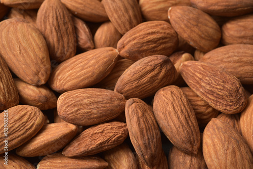 Close up photograph of dried almonds nuts with selective focus and details. Beautiful almonds background. Healthy eating and snack, whole foods. Source of protein and magnesium.
