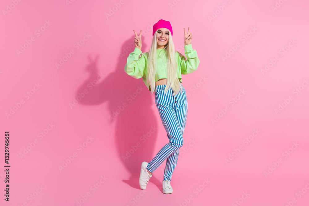 Young female in vibrant casual fashion posing against a pink background displaying peace gestures with a cheerful and stylish expression Young female in vibrant casual fashion posing against a pink background displaying peace gestures with a cheerful and stylish expression