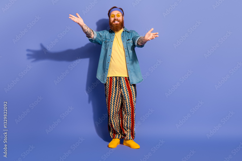 Fototapeta premium Stylish bearded man in vibrant casual wear posing on a purple background with a cheerful expression