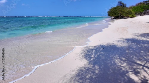 ocean coast with trees on tropical beach, turquoise sea water. Gili island Indonesia. Ideal for relaxation themes, vacation vibes and peaceful escape imagery, slow motion