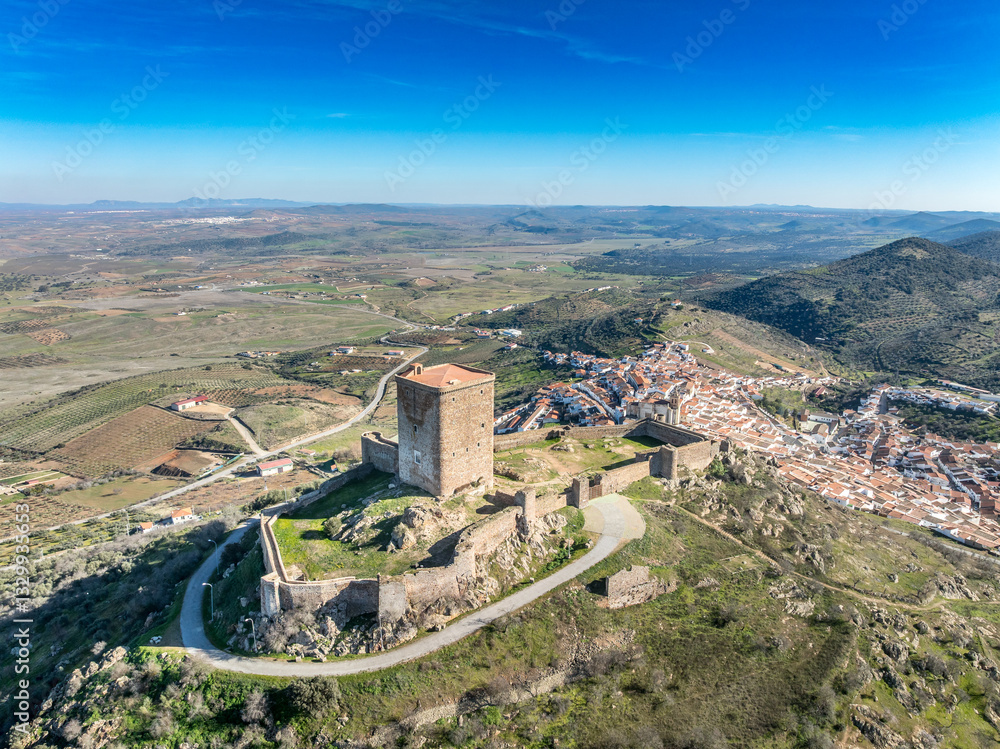 Aerial view of Feria castle in Spain, Gothic and Mudéjar style buildings, square keep, blue sky background