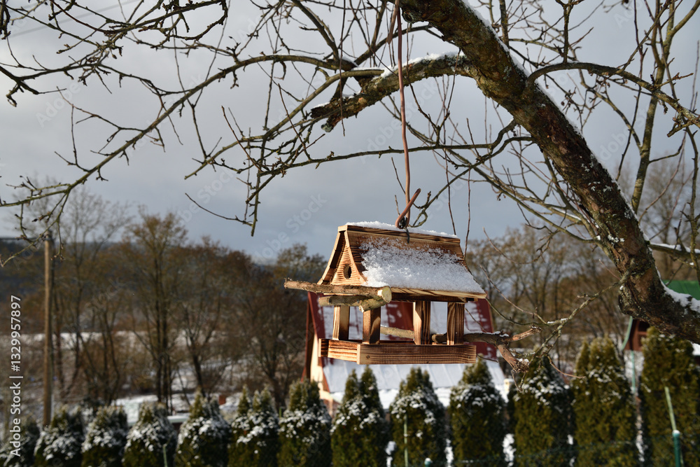 Handmade wooden birdhouse hanging on a tree branch in winter