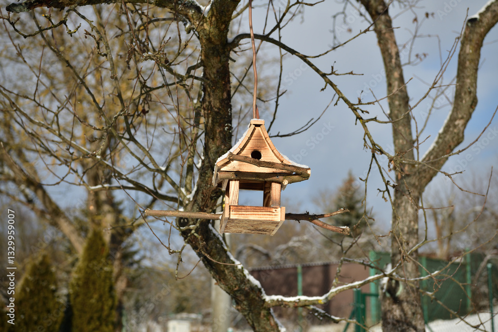 Handmade wooden birdhouse hanging on a tree branch in winter