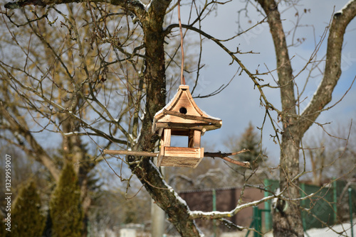 Obraz na płótnie Handmade wooden birdhouse hanging on a tree branch in winter w salonie