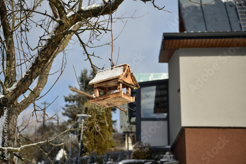 Handmade wooden birdhouse in the garden in winter near the house