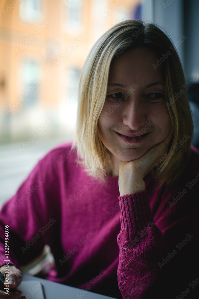 A close-up portrait of a woman writing in a notebook, her focused expression illuminated by natural light in a serene public setting.