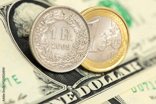 Auf einem US-Dollar-Schein liege eine Münze Schweizer Franken und eine Euromünze