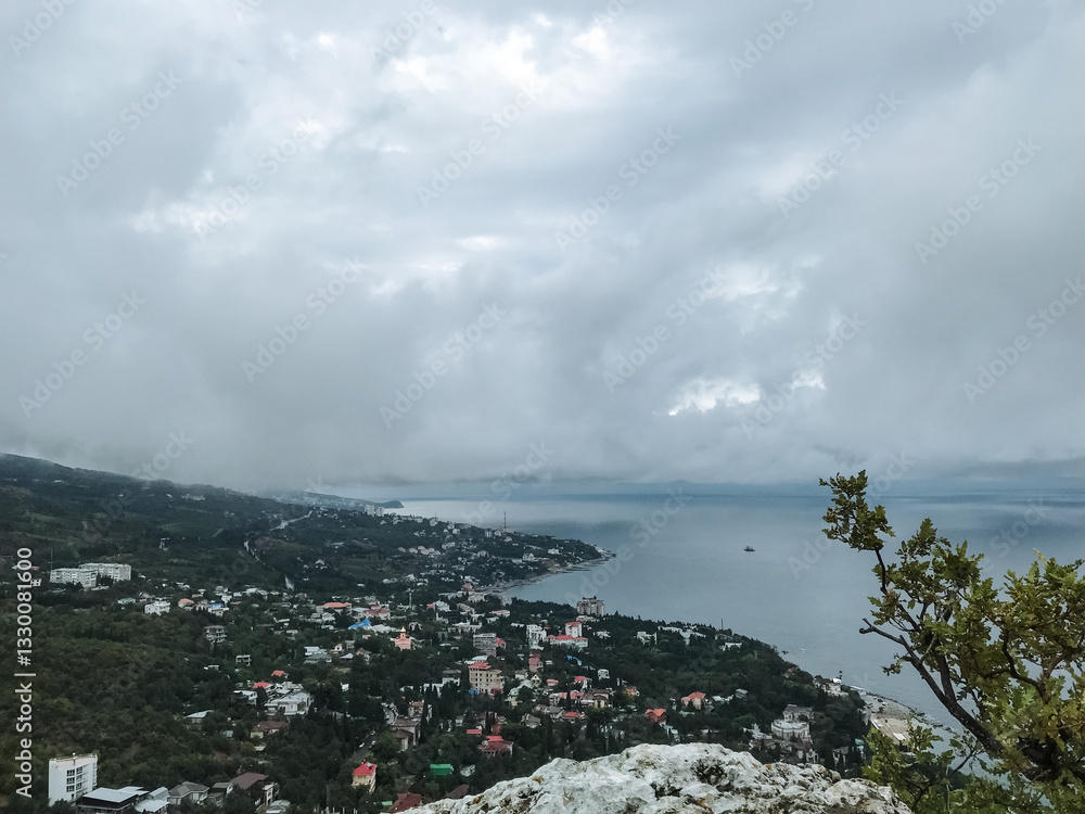 Fototapeta premium Imagine witnessing a breathtaking view of a vibrant cityscape from a high cliff that dramatically overlooks a sparkling body of water, offering a perfect blend of nature and urban life