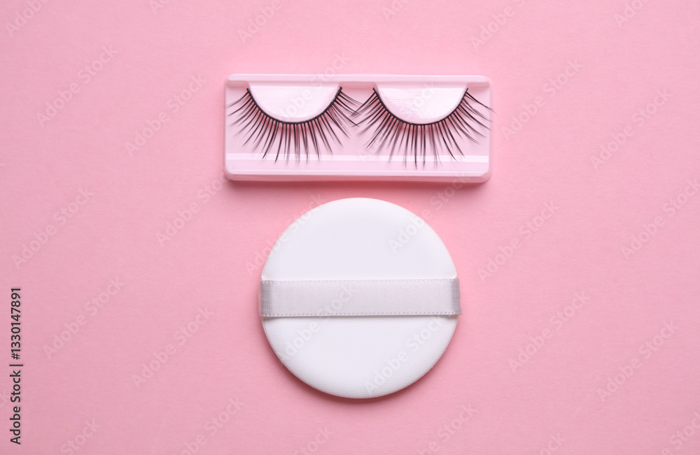 Obraz premium False eyelashes and makeup sponge on pink background. Beauty concept