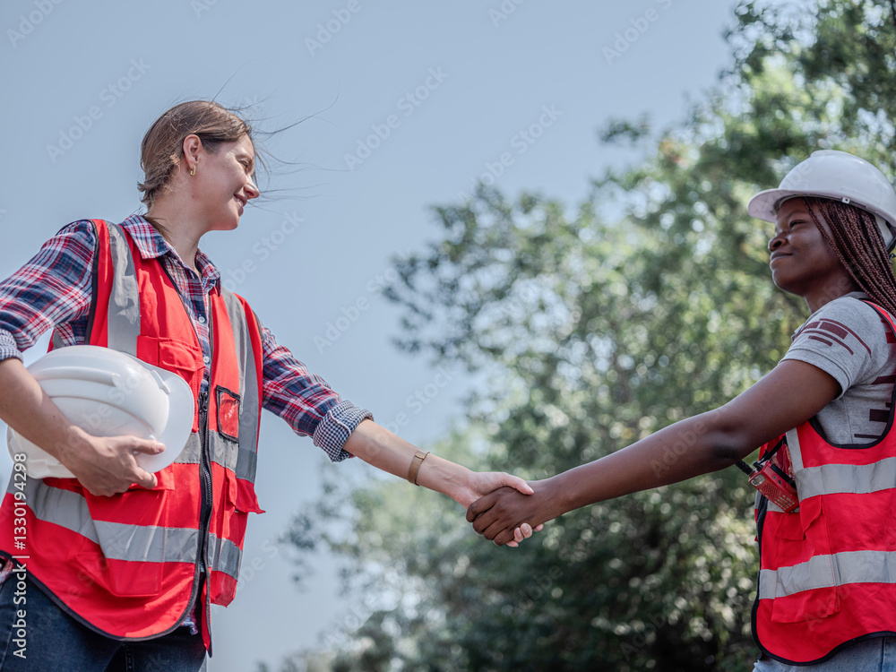 Female architectural engineer with civil planner assistant and inspector before working on rail transport project at construction site. Handshake for successful concept..