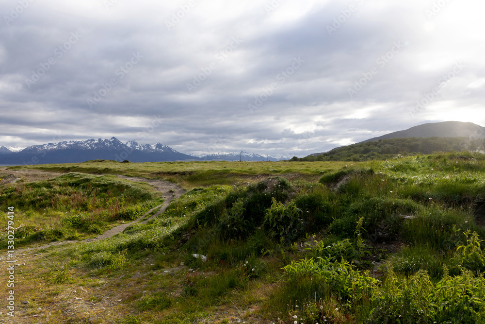 A large green field cut through by a marked path on the left side of the image, the landscape is being illuminated by a diffuse light as the sky is a little cloudy. A large green field cut through by a marked path on the left side of the image, the landscape is being illuminated by a diffuse light as the sky is a little cloudy.