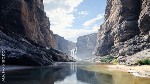 Explore stunning canyon landscapes with towering rock formations and a tranquil river. The waterfall cascades amid vibrant nature, showcasing beautiful scenery and clear skies