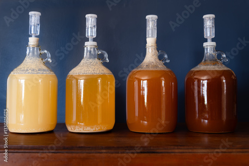 Quadro su tela Four carboys filled with liquid varying in color from light gold to dark amber w