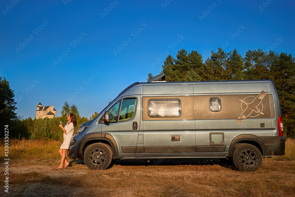 An offroad camper van parked in nature with a relaxed woman traveler enjoying the evening sun near Bobolice Castle, Poland. Ideal for: camper lifestyle, slow travel, and outdoor adventure themes. An offroad camper van parked in nature with a relaxed woman traveler enjoying the evening sun near Bobolice Castle, Poland. Ideal for: camper lifestyle, slow travel, and outdoor adventure themes.