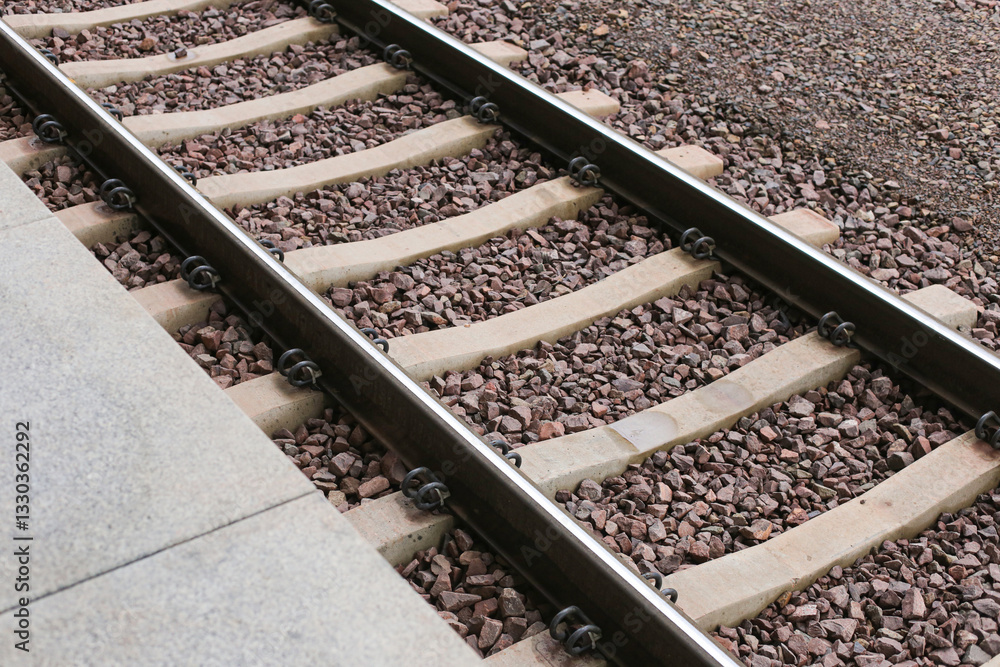 Railway tracks with steel rails and gravel stones. Train station platform transportation route. Industrial railroad junction leading to a railway terminal. Tracks stretching into distance. Railway tracks with steel rails and gravel stones. Train station platform transportation route. Industrial railroad junction leading to a railway terminal. Tracks stretching into distance.