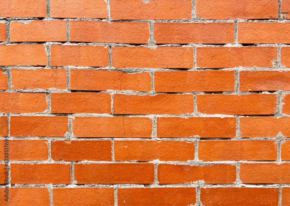 Obraz premium Texture of a red brick wall with lines of cement joints. Protruding bricks. Concept fashion, brutal, style background close-up for advertising. Text space.