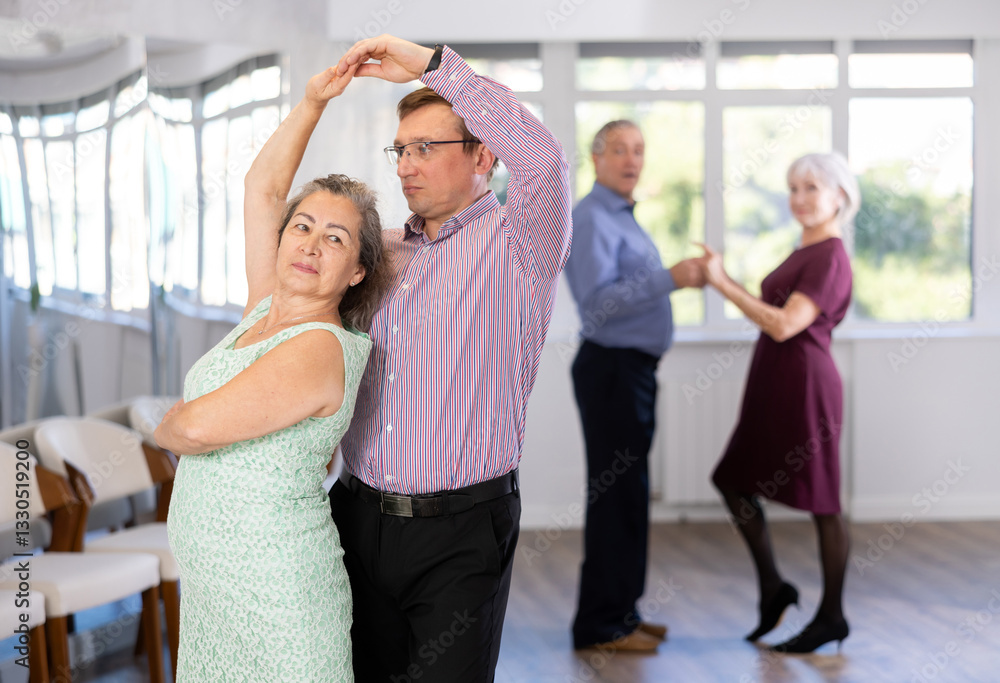 Naklejka premium Couple of adult man and elderly woman dancing waltz in studio