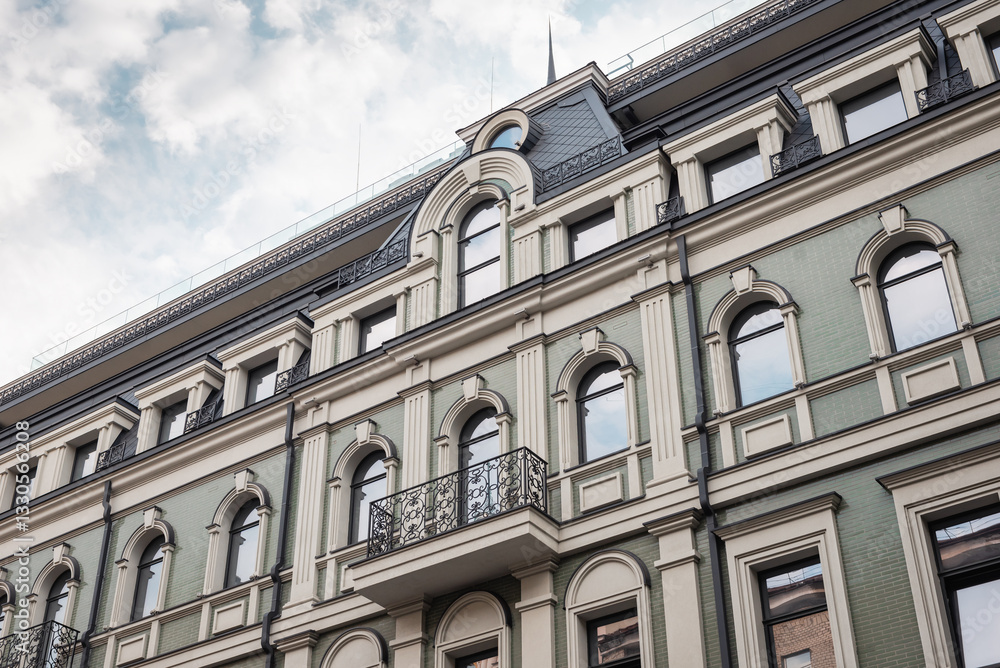 Upper part of a facade of an old green building with beige window surrounds. Looking up at the rooftop of a building in old town. Upper part of a facade of an old green building with beige window surrounds. Looking up at the rooftop of a building in old town.