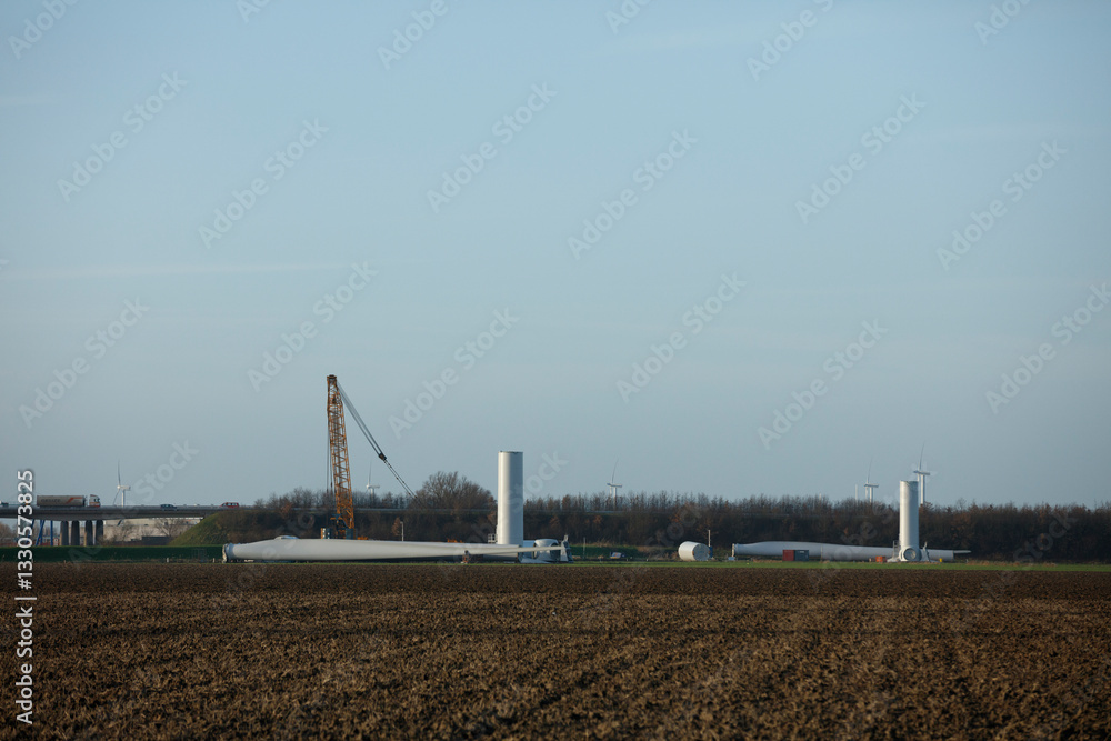Wind turbine construction near a rural area with cranes and equipment under a clear sky Wind turbine construction near a rural area with cranes and equipment under a clear sky