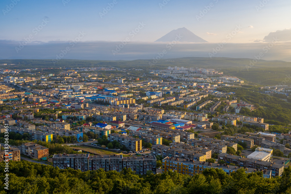 Morning cityscape. Top view of the buildings and streets of the city. Residential urban areas at sunrise. Koryaksky volcano in the distance. Petropavlovsk-Kamchatsky, Kamchatka Krai, Russian Far East.