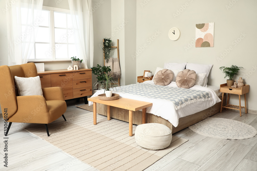 Obraz premium Interior of light bedroom with bedside tables, armchair, chest of drawers and big bed