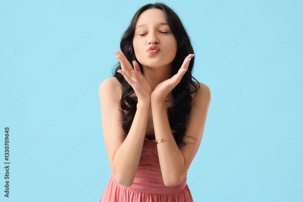Beautiful happy teenage girl in stylish pink prom dress blowing kiss on blue background Beautiful happy teenage girl in stylish pink prom dress blowing kiss on blue background