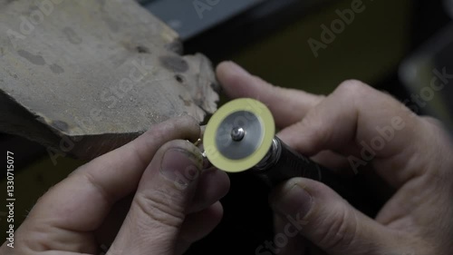 Hand processing of a jewelry piece, close-up. A man is processing a jewelry piece, grinding. Jewelry factory
