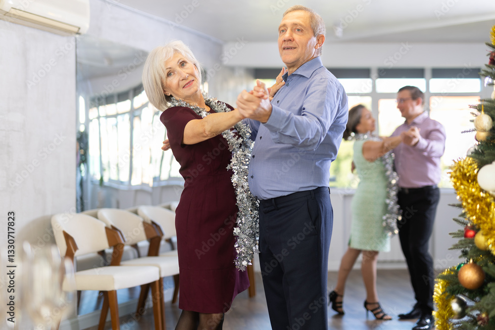 Obraz premium Happy couples mature male and female dancing bachata kizomba movement in modern dance room during celebration Christmas and New Year