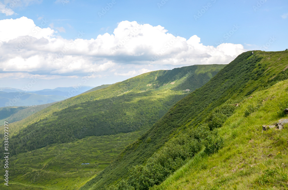 Panoramic view of lush green mountain ridge covered in dense vegetation stretch under sky filled with clouds. Perfect for travel, nature, and landscape concepts. Svydovets, Carpathian Mountains Panoramic view of lush green mountain ridge covered in dense vegetation stretch under sky filled with clouds. Perfect for travel, nature, and landscape concepts. Svydovets, Carpathian Mountains