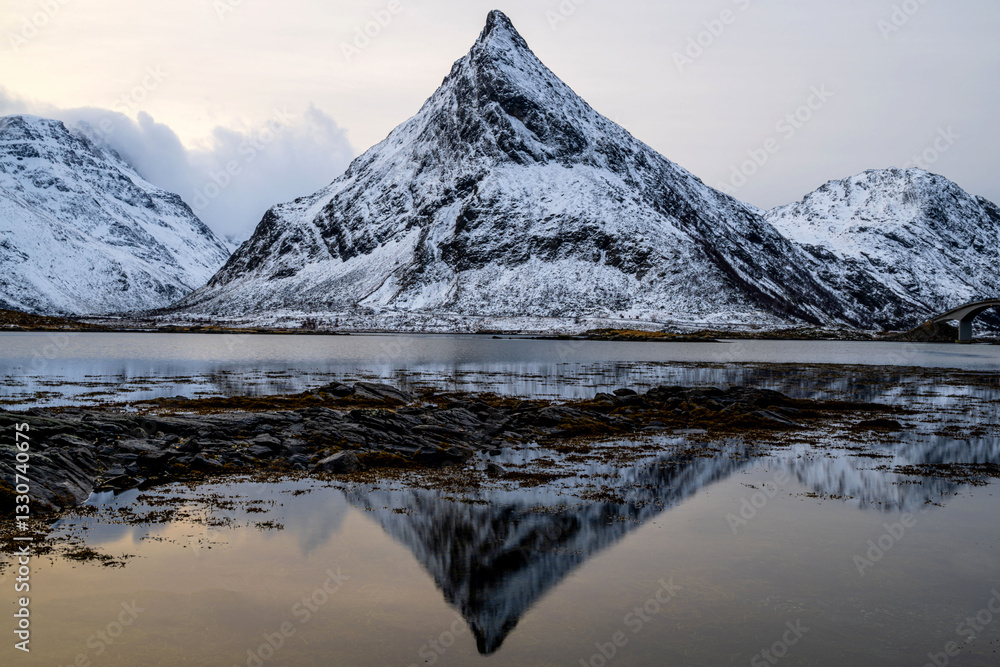 Fototapeta premium Reflection of snow-covered mountain range in a lake with calm water, Fredvang, Lofoten, Norway