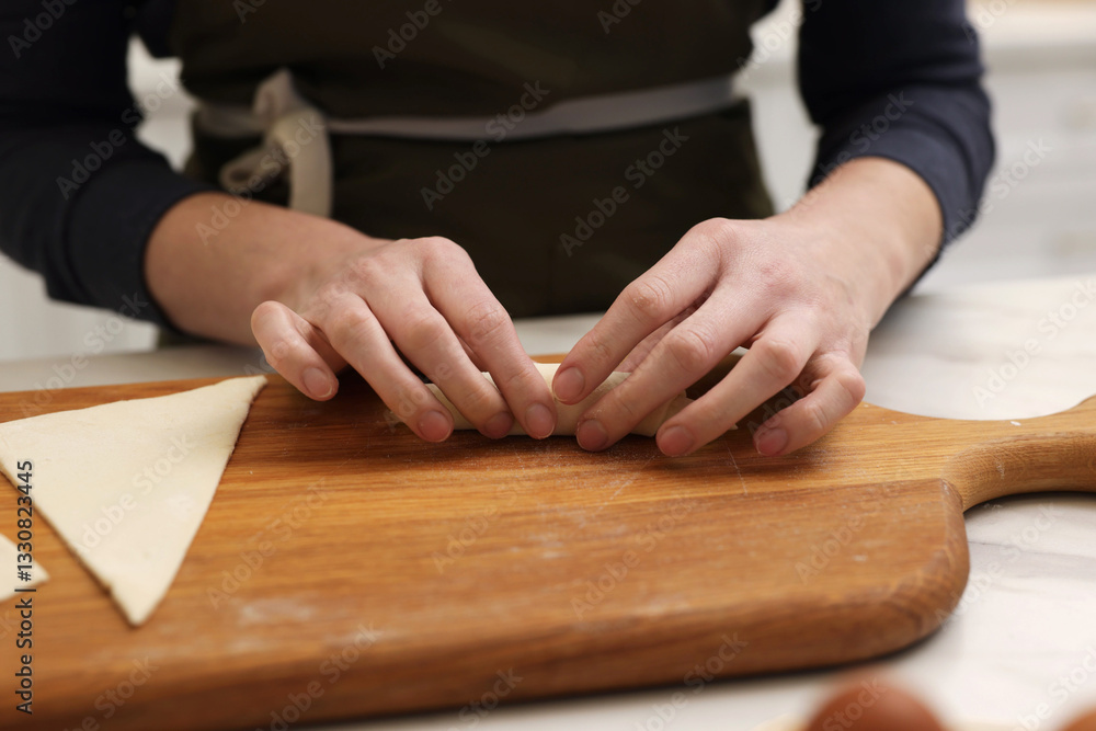 Woman rolling croissant from fresh dough at light table, closeup Woman rolling croissant from fresh dough at light table, closeup