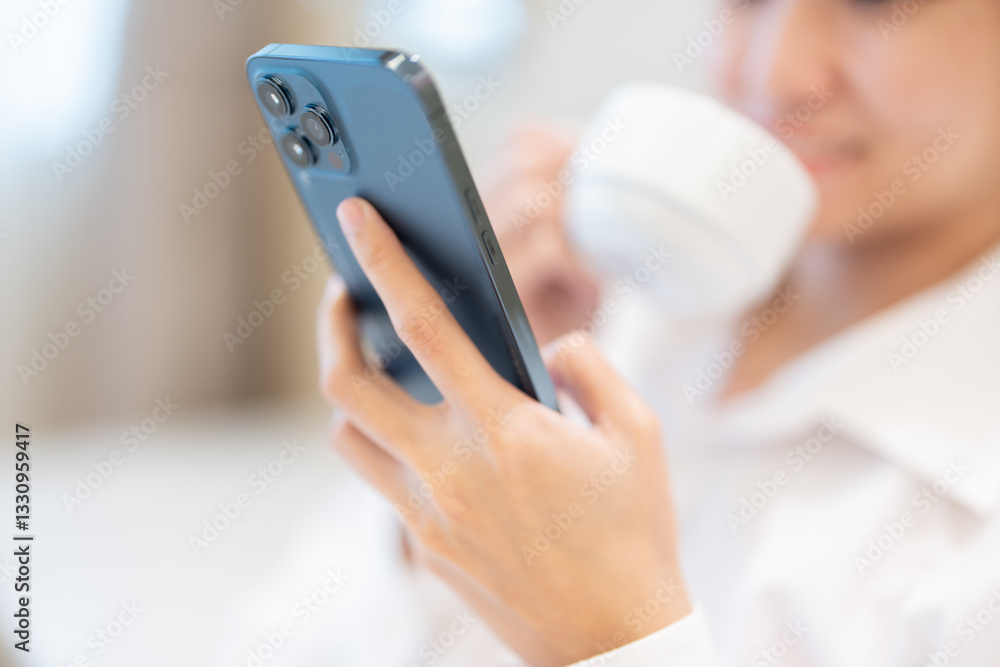 Close-up of Asian woman's hands using smartphone as she relaxes in her hotel room, sips a drink and lets herself relax and feel grateful for the wonderful holiday she had. Close-up of Asian woman's hands using smartphone as she relaxes in her hotel room, sips a drink and lets herself relax and feel grateful for the wonderful holiday she had.