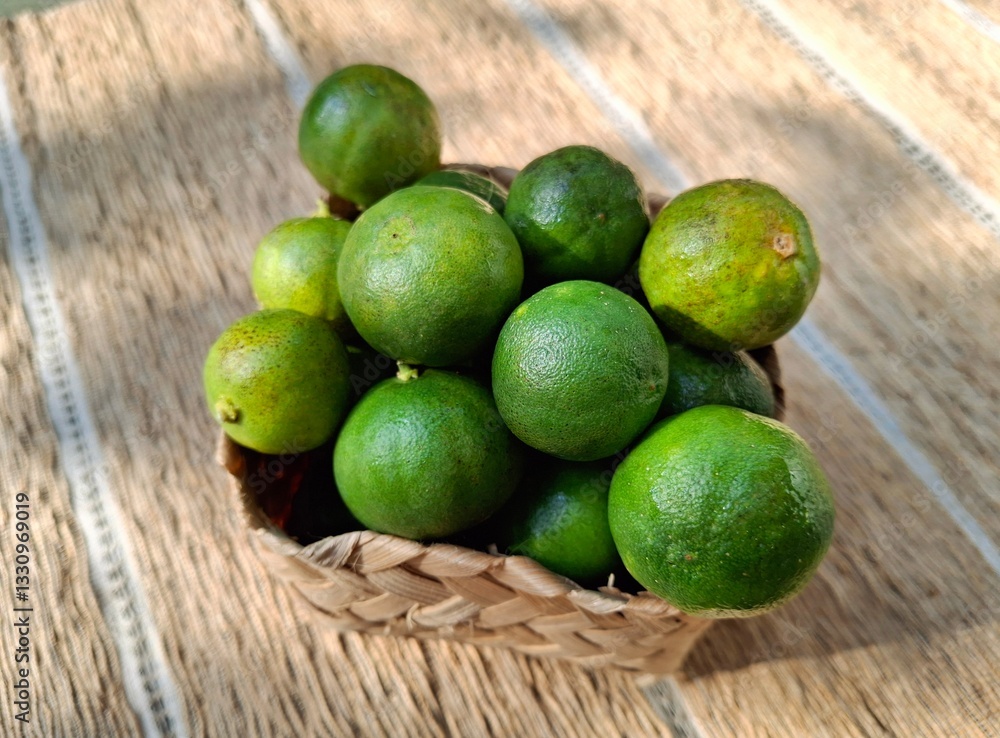 Fresh limes in a woven basket on textured background Fresh limes in a woven basket on textured background
