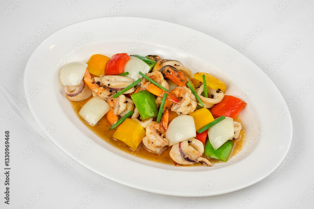 This image shows a white oval plate with stir-fried seafood, including squid and shrimp, mixed with bell peppers, onions, and green beans in a savory sauce. This image shows a white oval plate with stir-fried seafood, including squid and shrimp, mixed with bell peppers, onions, and green beans in a savory sauce.