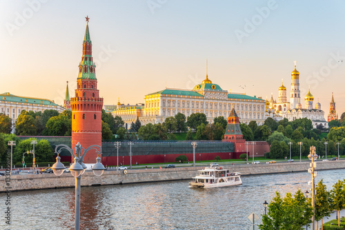 View of Kremlin with Vodovzvodnaya tower, Grand Kremlin Palace from repaired Bolshoy Kamenny Bridge in Moscow city on sunny summer day. Cruise ship sails on the Moscow river